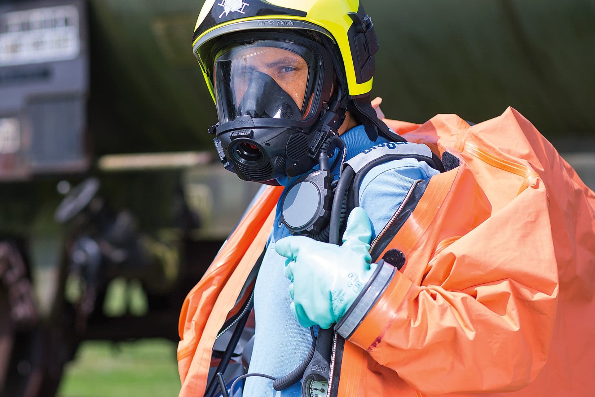 Firefighter using a control unit with Push-To-Talk button during hazmat application.